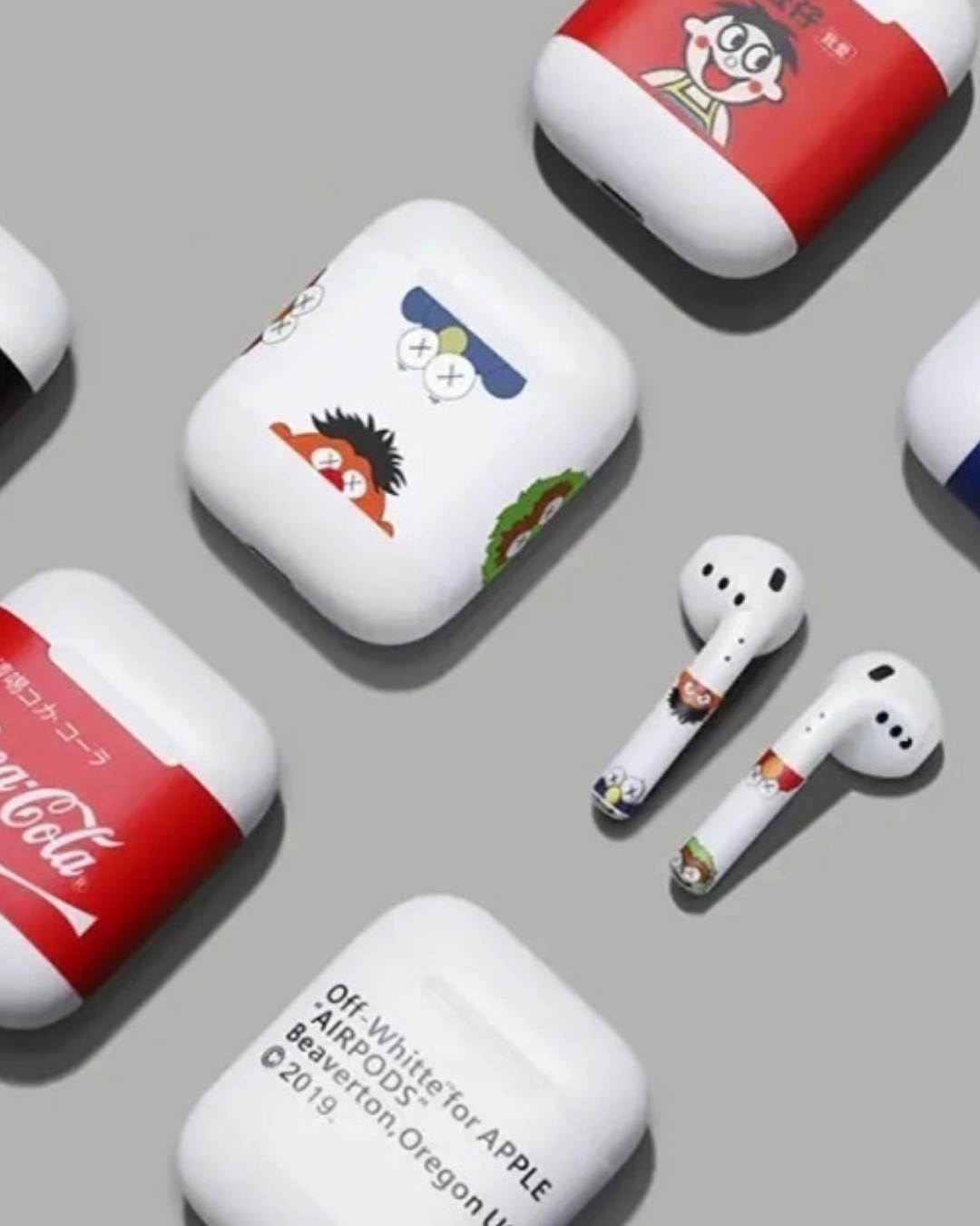 Plusieurs AirPods blancs et leurs boîtiers de charge, ornés de divers motifs de marques et de personnages