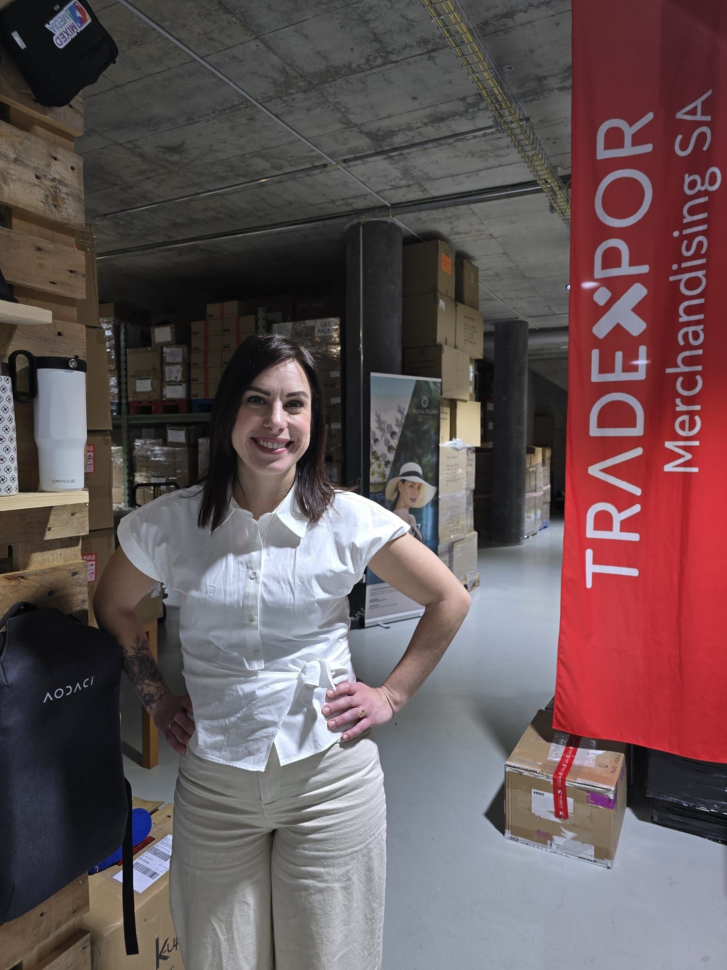Un immeuble de bureaux de cinq étages avec une façade en verre, des moulures horizontales blanches et une entrée paysagée