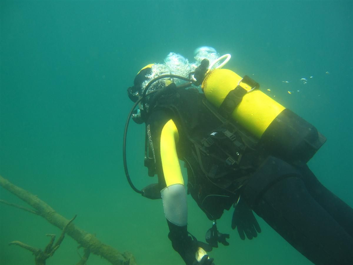 Een duiker in een geel pak zwemt in het water.