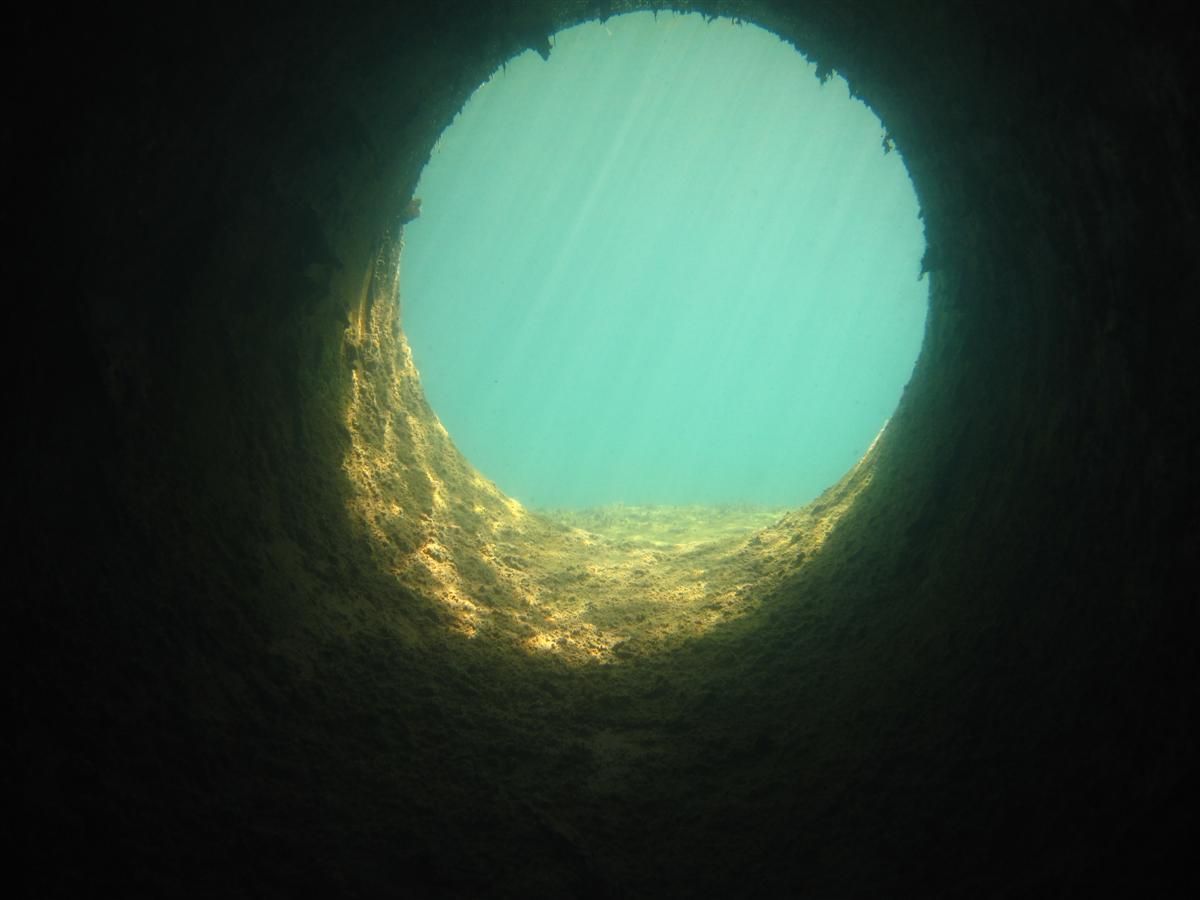 Een zicht op de oceaan door een gat in een pijp.