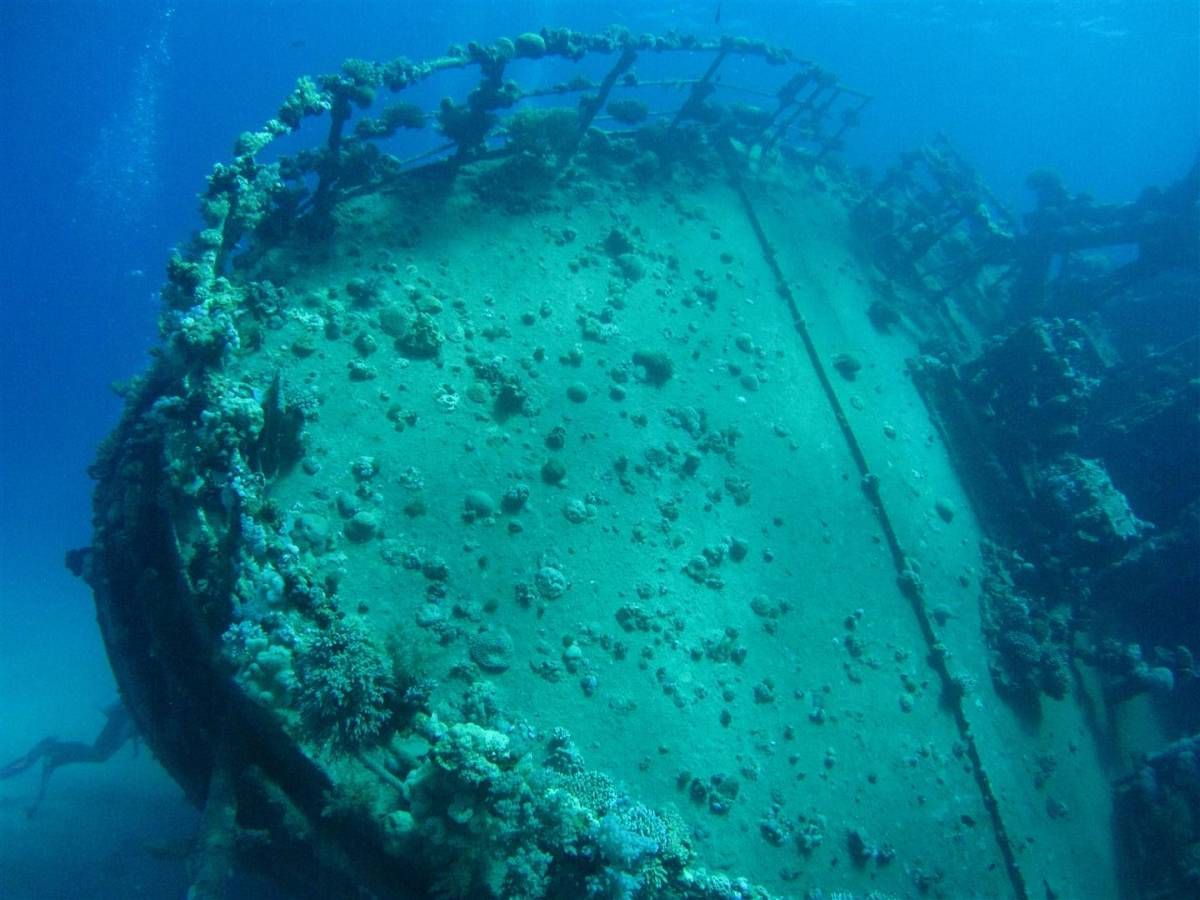 Een groot scheepswrak drijft bovenop een koraalrif in de oceaan.
