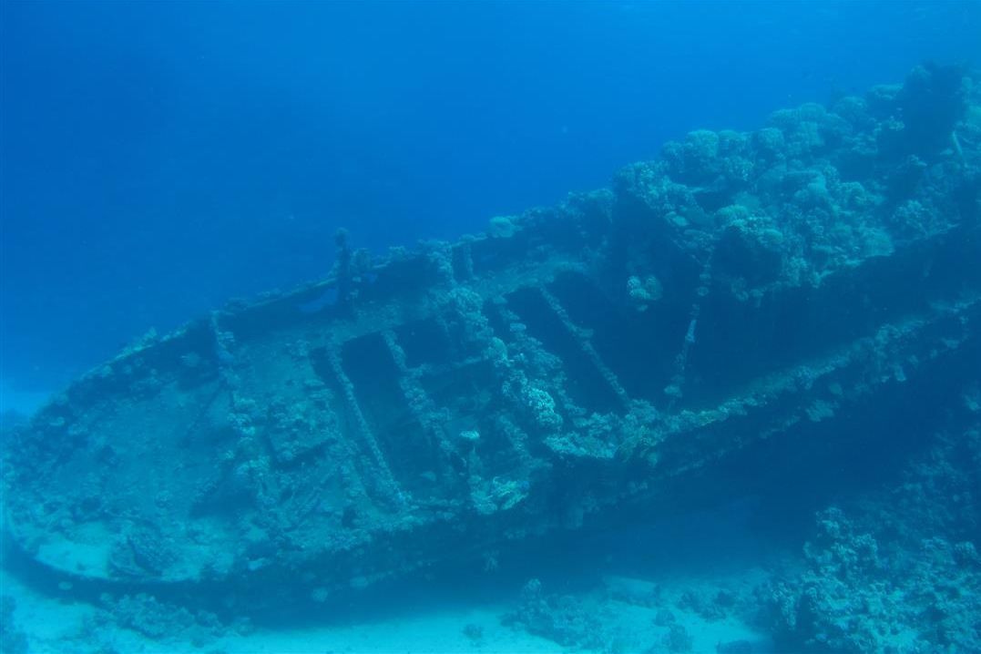 Een groot scheepswrak drijft bovenop een koraalrif in de oceaan.