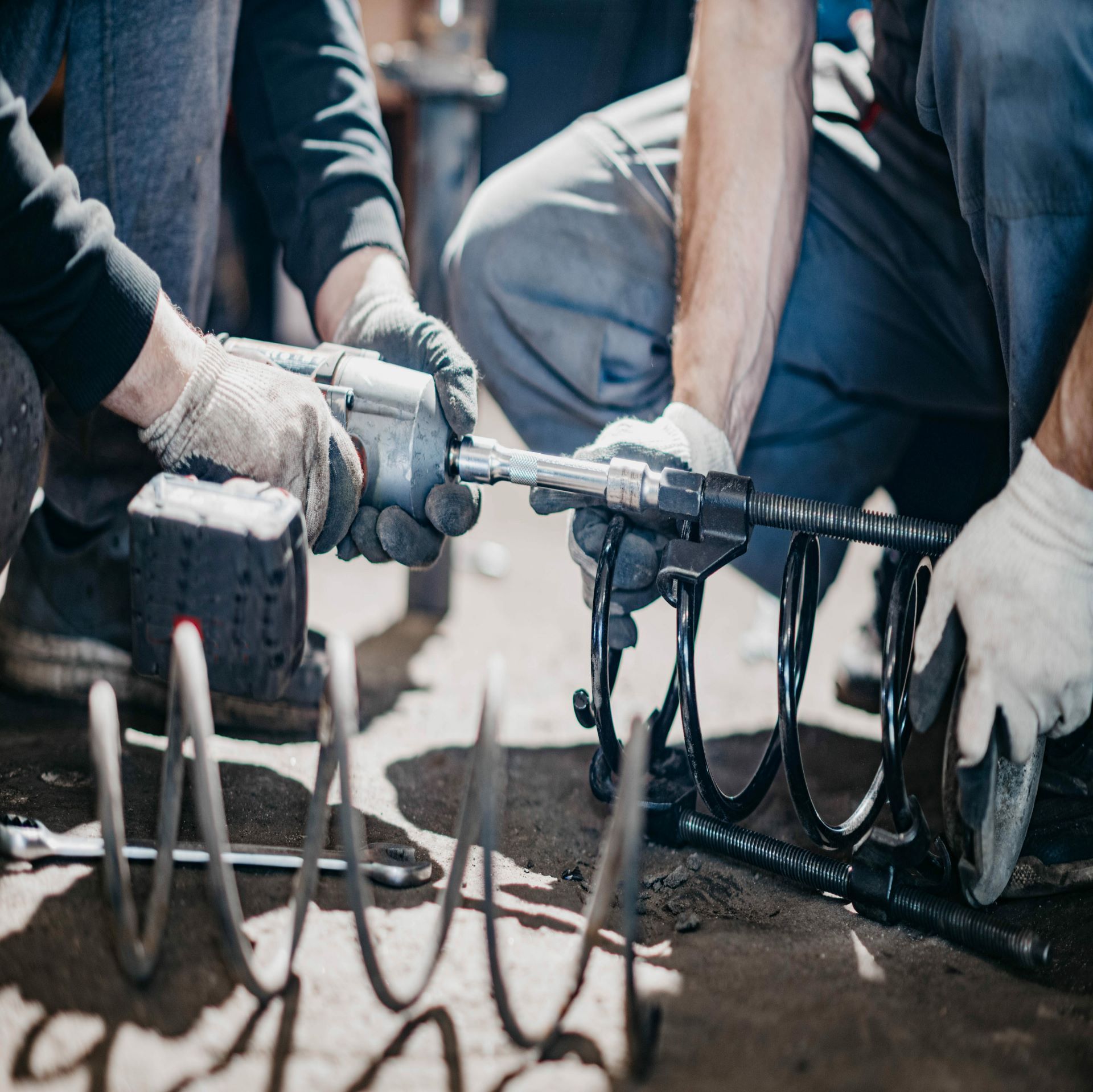 Two mobile mechanic are working on a spring with a wrench.