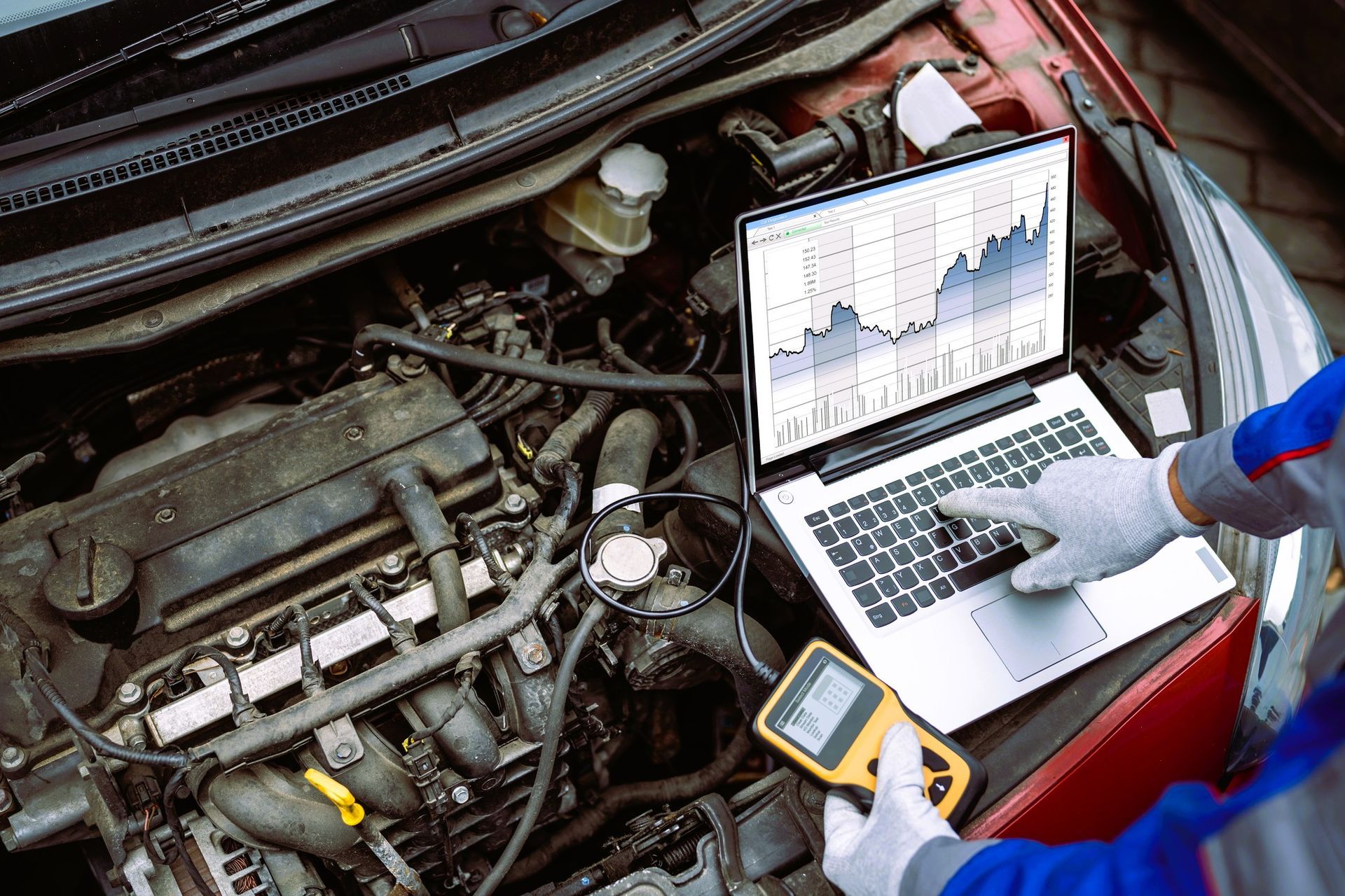 Mechanic running computer diagnostics on car engine with laptop and scanner