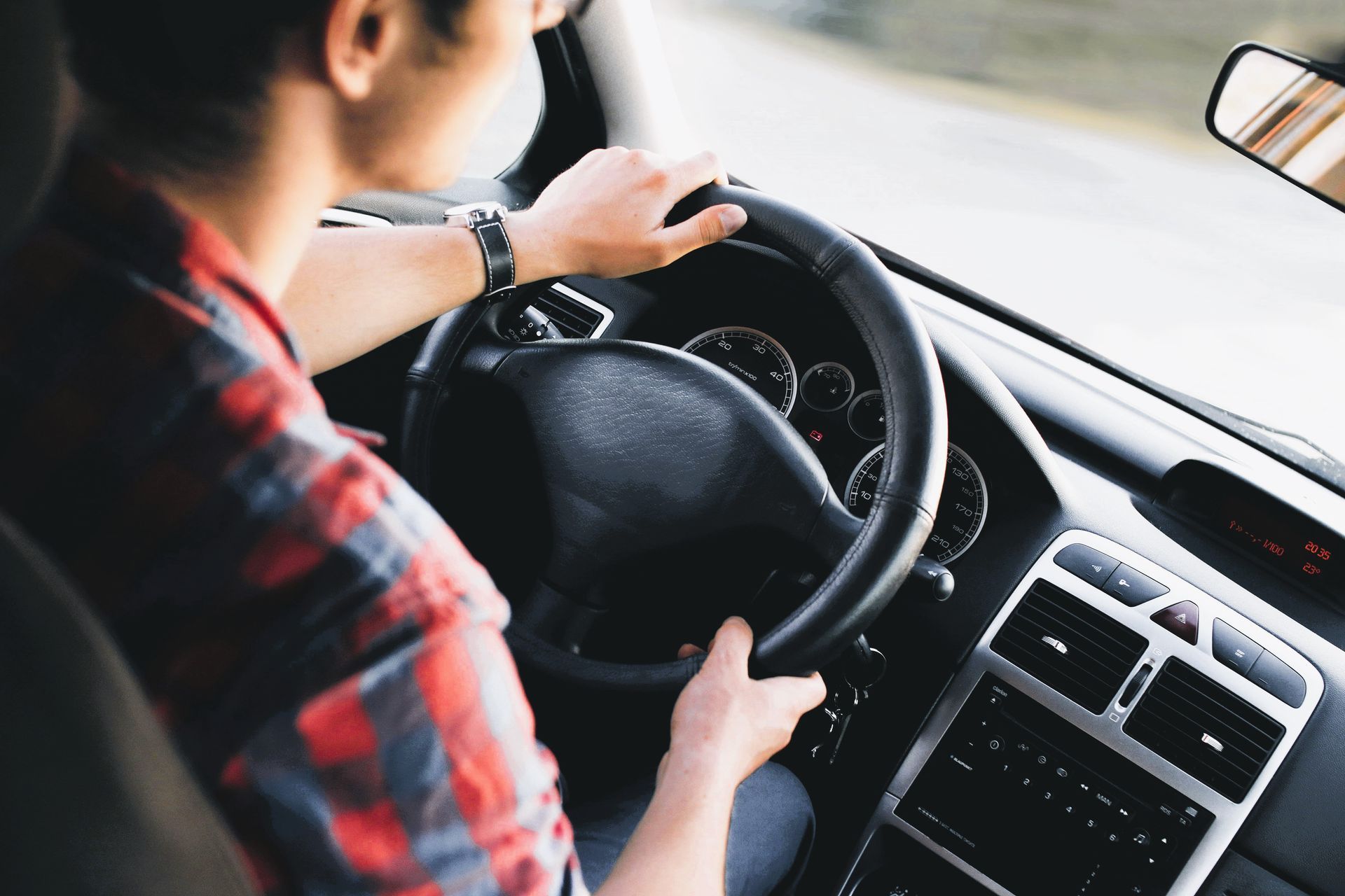 Close-up of a man’s hand gripping the steering wheel while driving