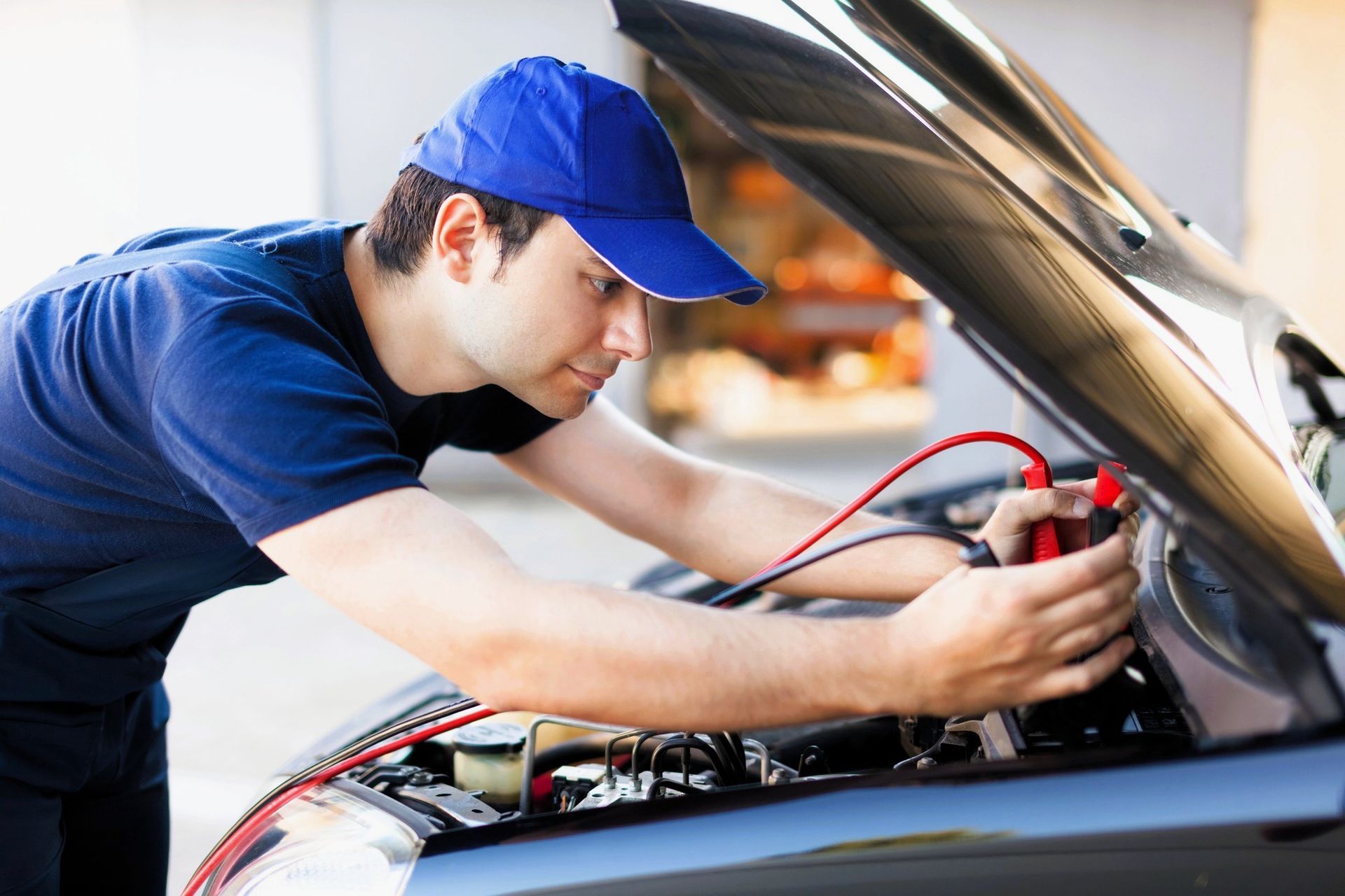 Mechanic connecting jumper cables or a battery charger to a car battery