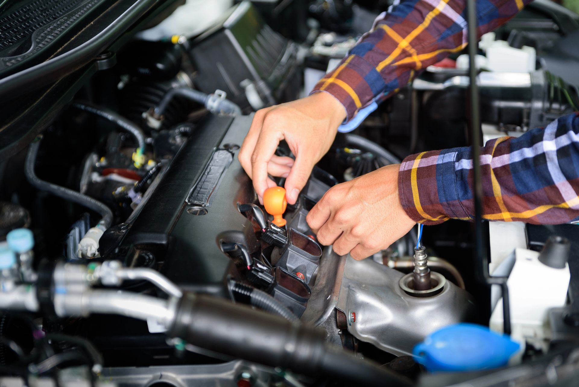 Mechanic inspecting car engine for unusual noise detection.