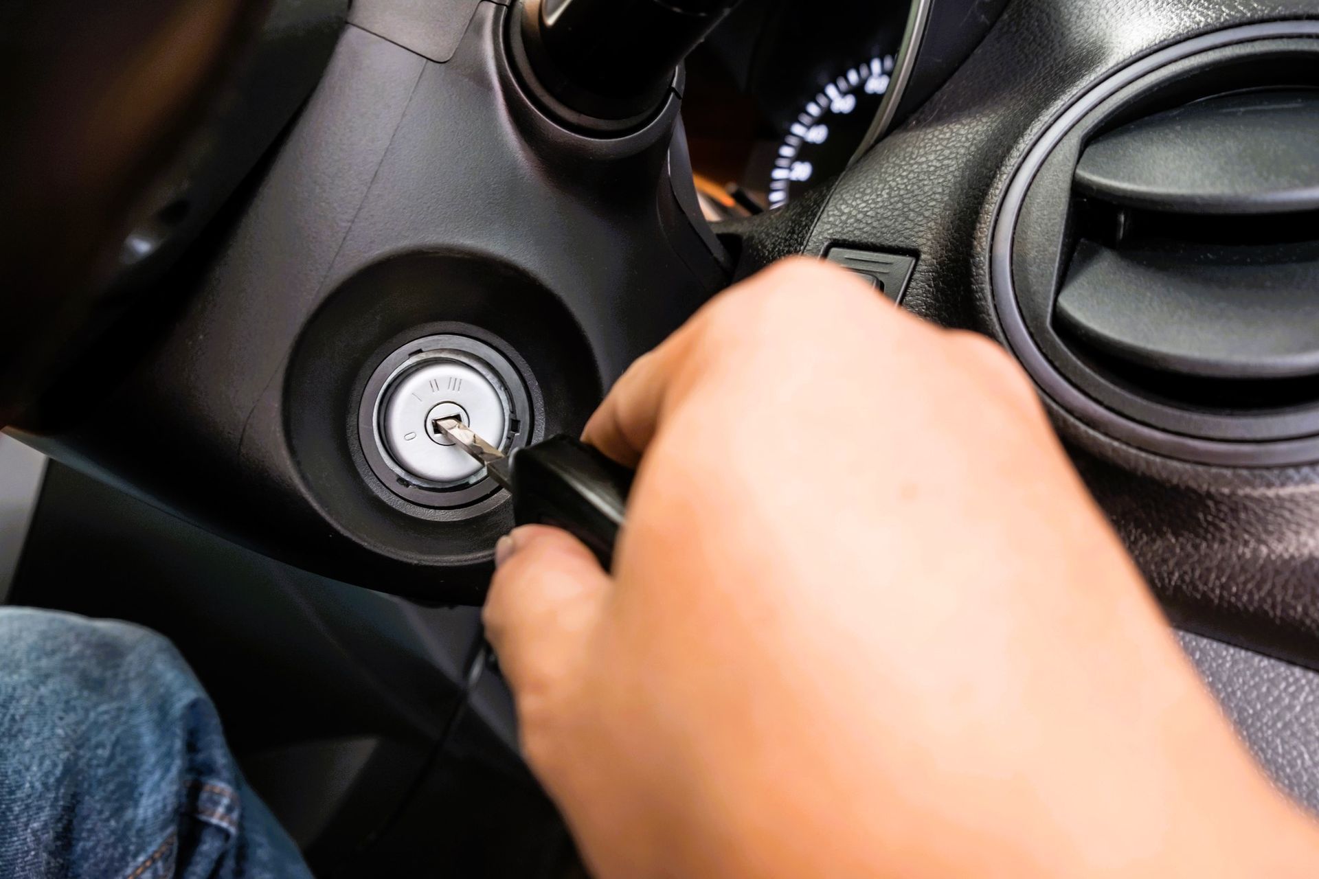 Hand turning a key in a vehicle's ignition switch to activate the car starter