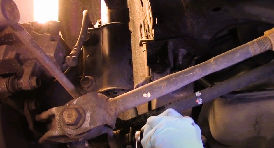 Expert mechanic diagnosing rear suspension noise in a car's suspension system