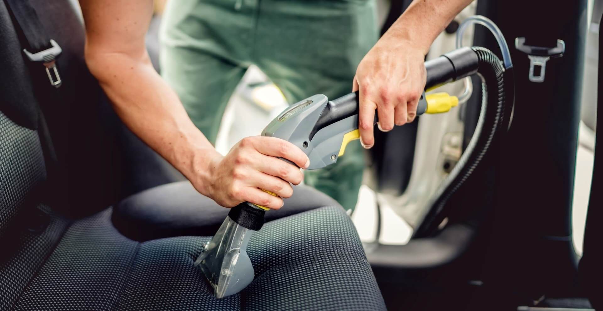 Man vacuuming his car seats to keep it clean and new-looking