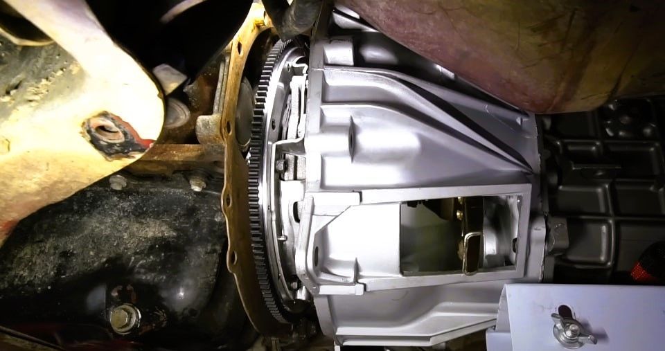 Car's flywheel and new clutch assembly viewed from underneath the vehicle.