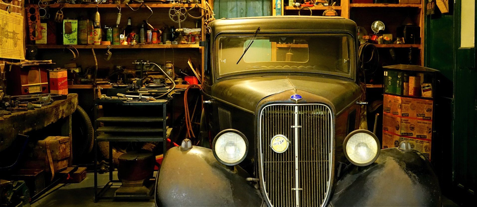 an old, classic car parked in a garage full of tools