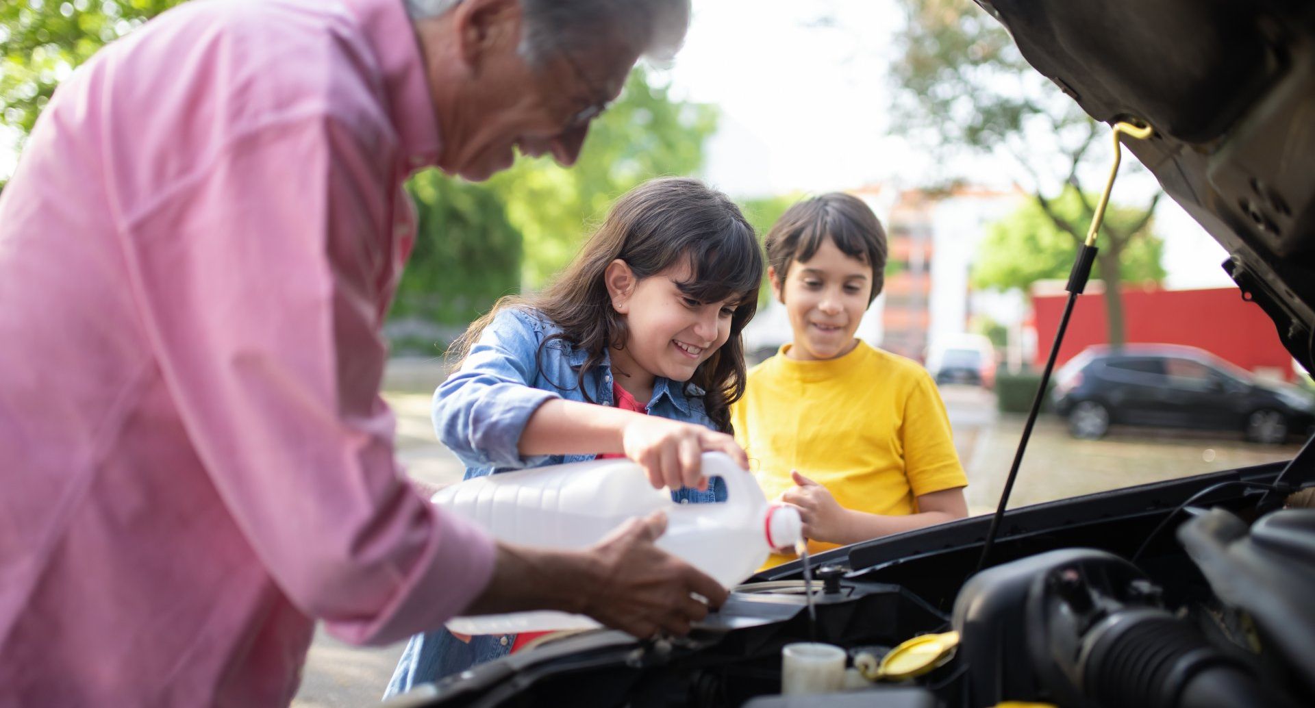 Man with grandchildren filling the wiper fluid of a car