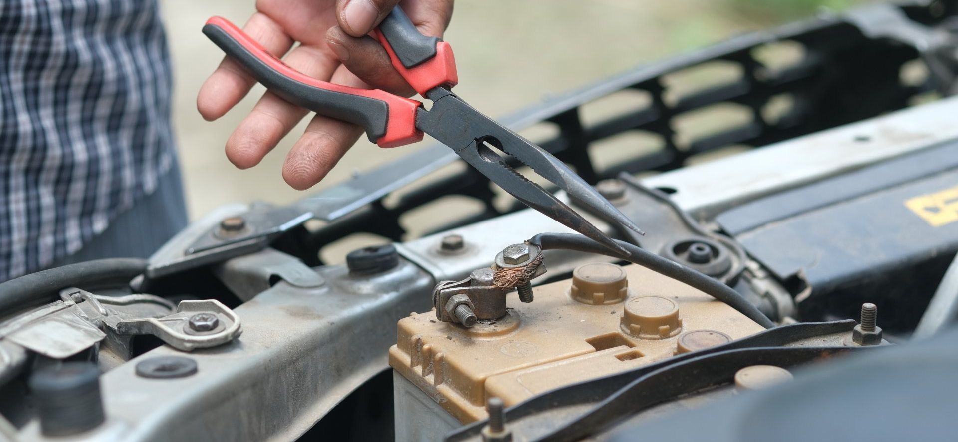 man uses tool to fix car battery
