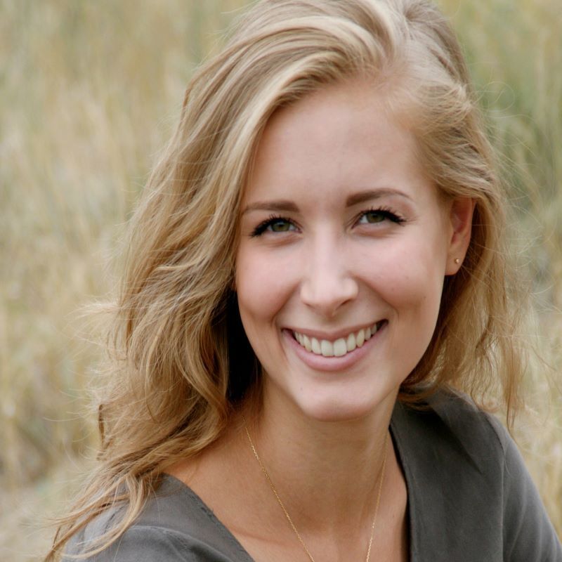 A woman with long blonde hair is smiling for the camera