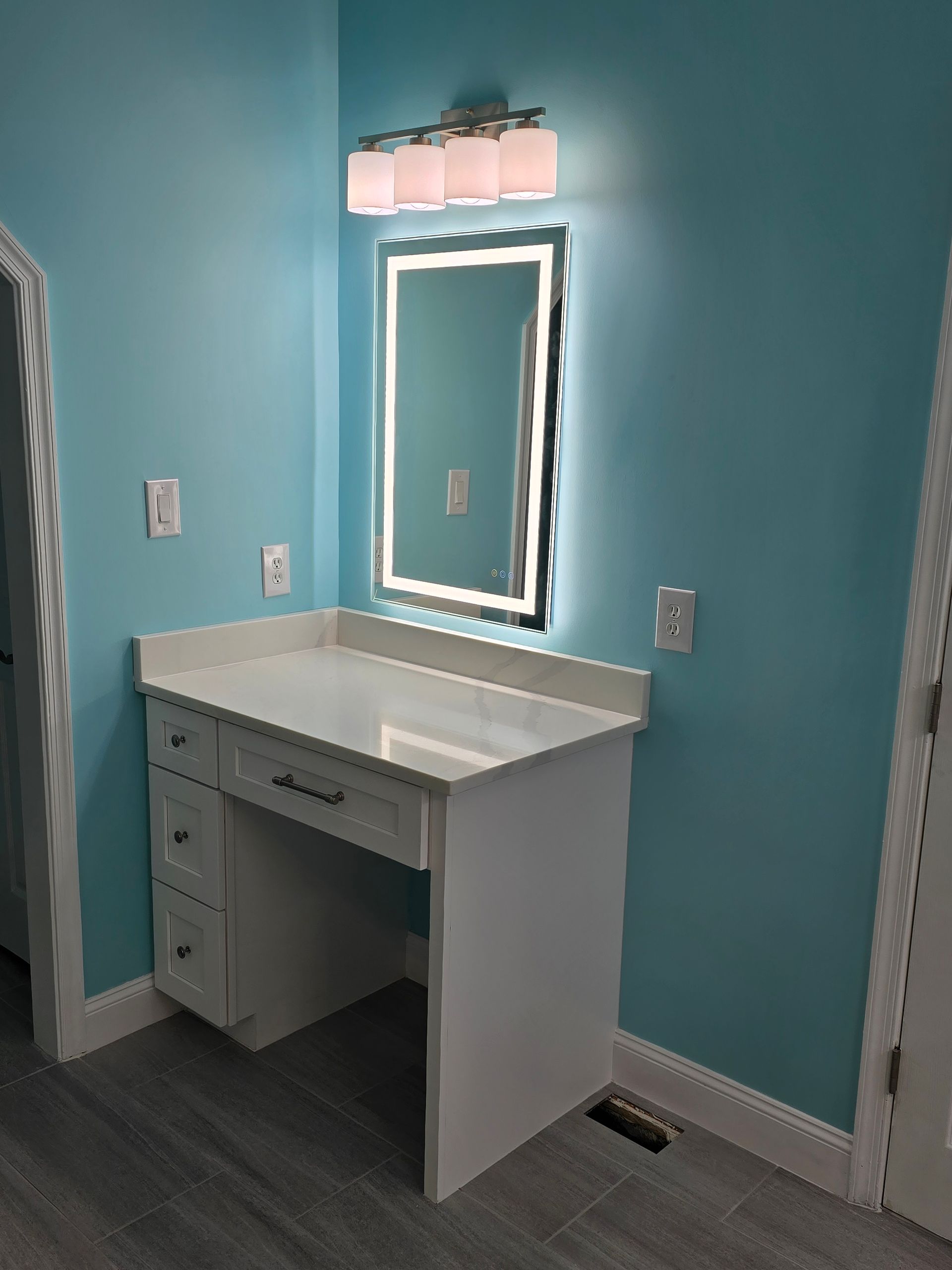White vanity with countertop and mirror in a blue-painted room.