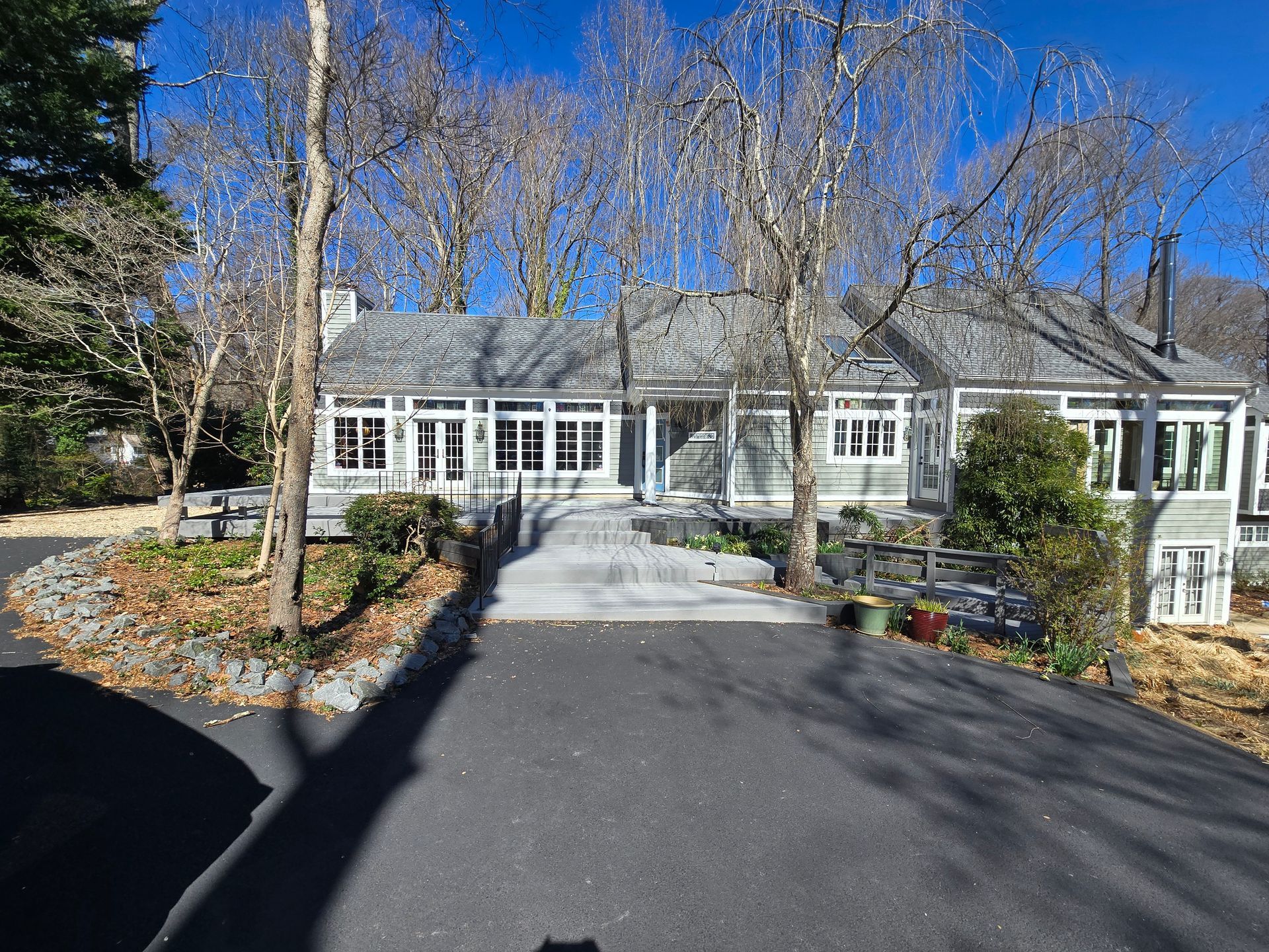 Gray house with many windows and a driveway on a sunny day.