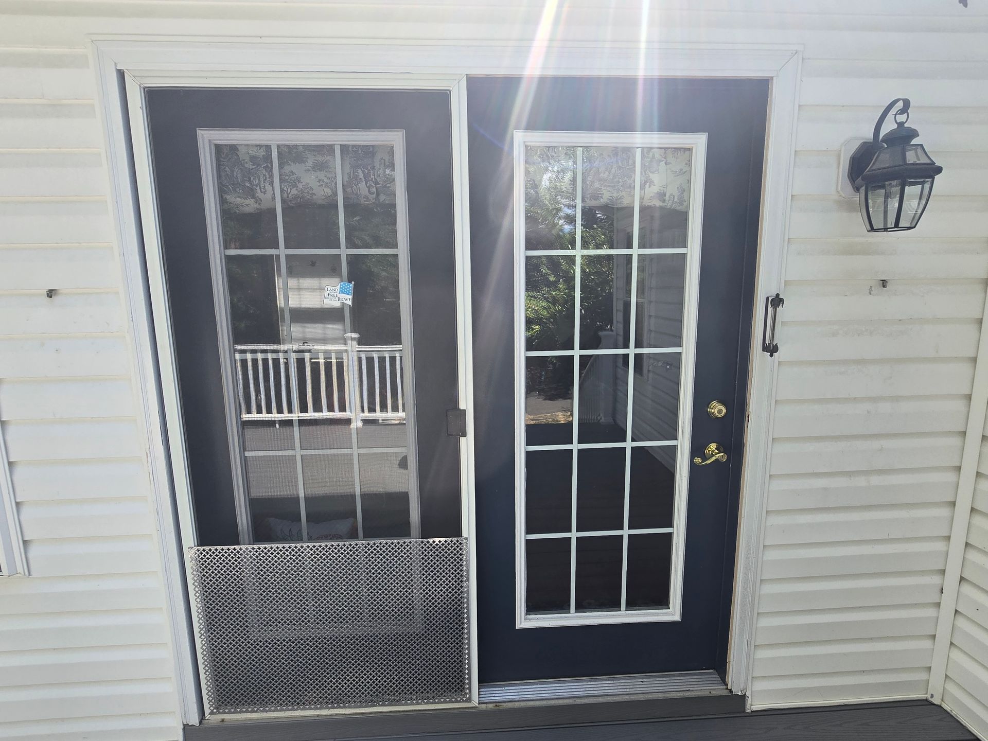 Two glass doors with white frames and a black door frame, outdoor setting with a light fixture on the right.