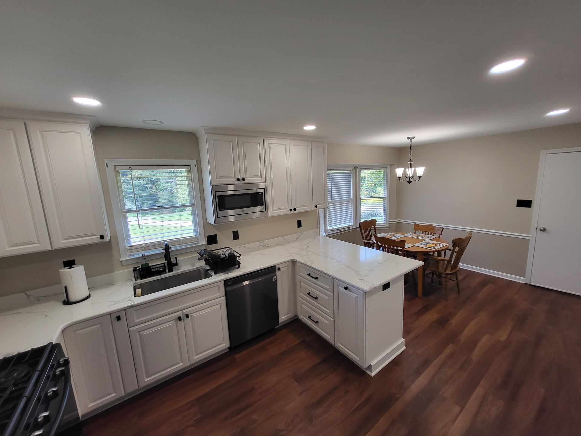 Modern kitchen with white cabinets, stainless steel appliances, and a dining area.