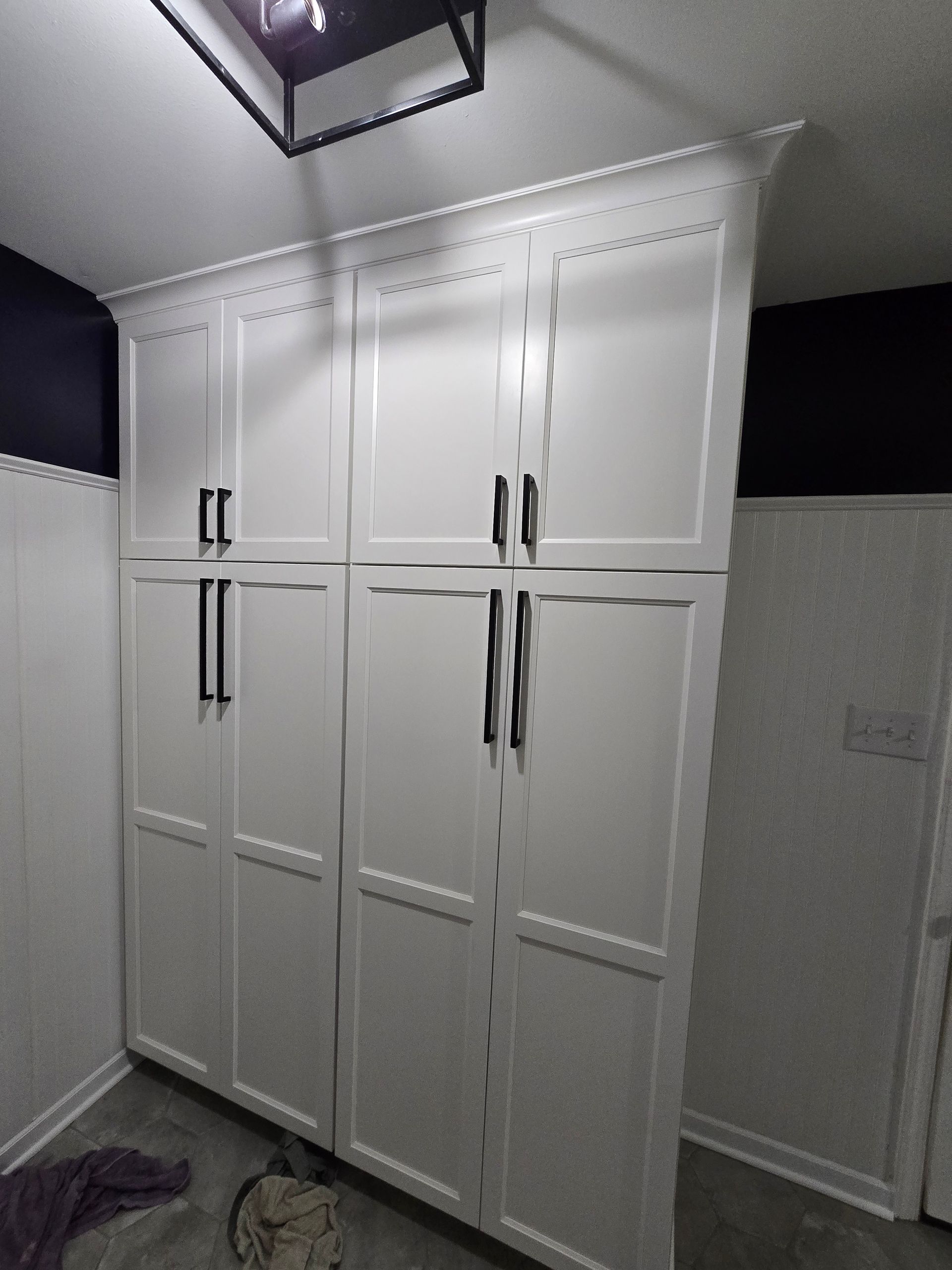 Tall white storage cabinets with black handles, in a room with white and dark blue walls.