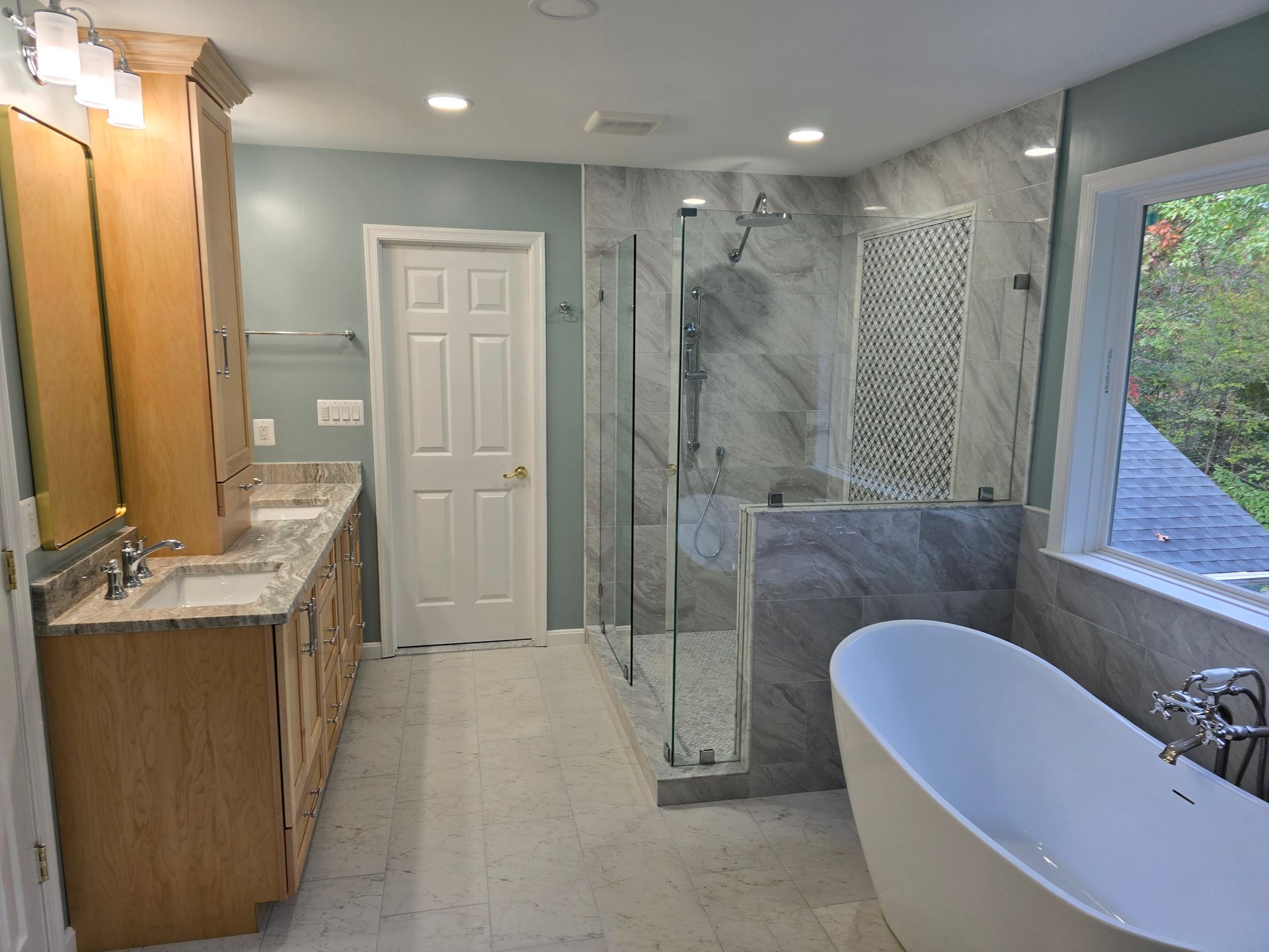 Newly renovated bathroom with a shower, bathtub, and vanity. Gray and beige tones, natural light.