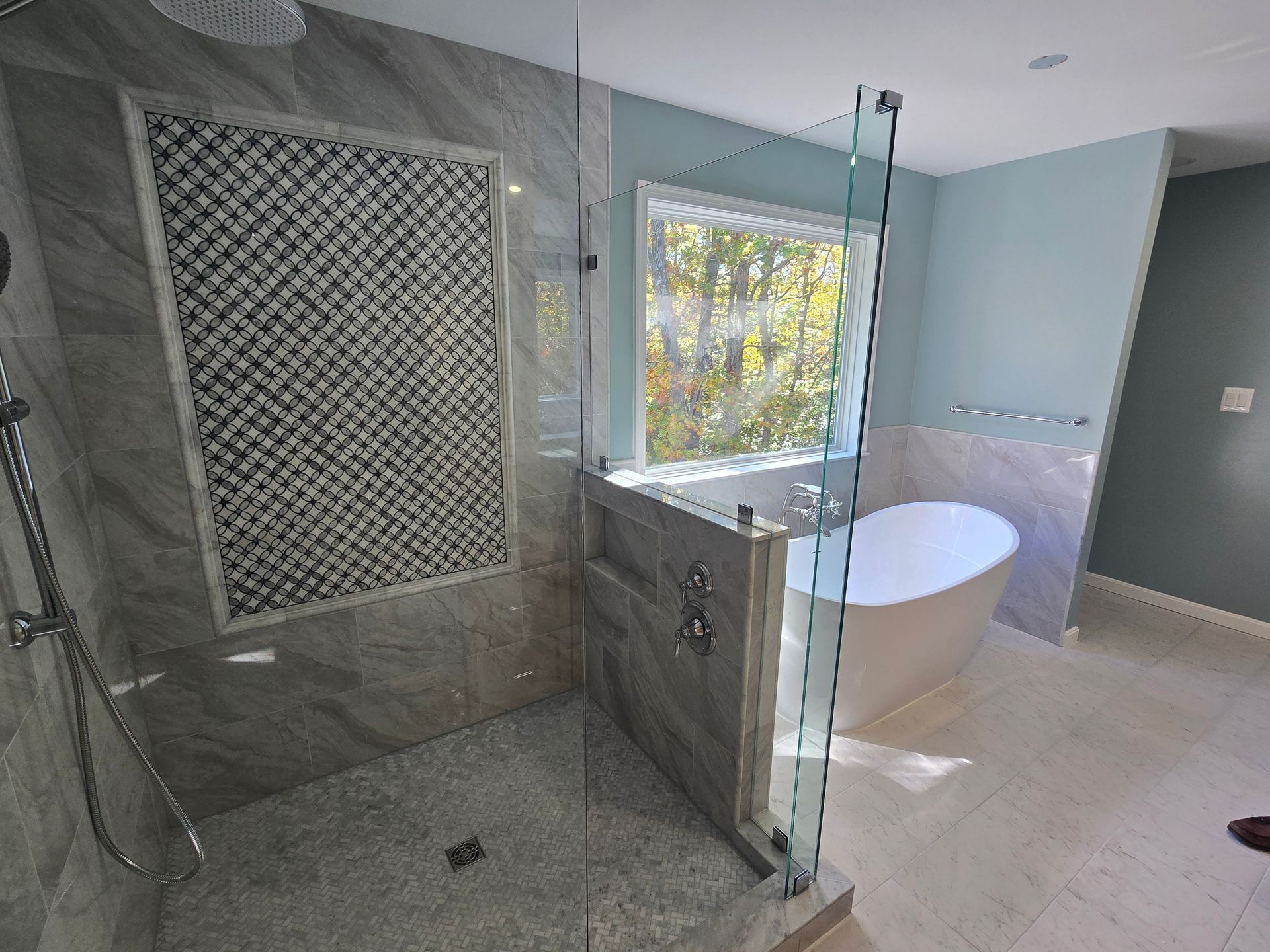 Modern bathroom with glass shower, soaking tub, and mosaic tile accent wall.