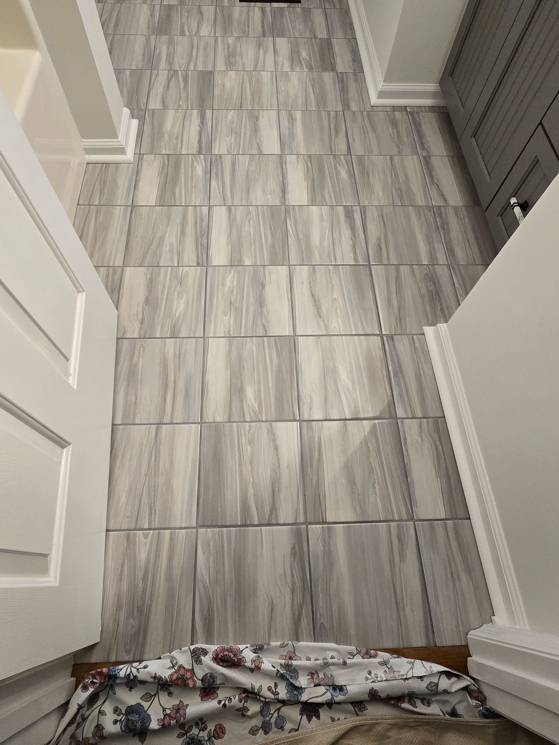 Bathroom floor with rectangular gray and white tiles, viewed from doorway.