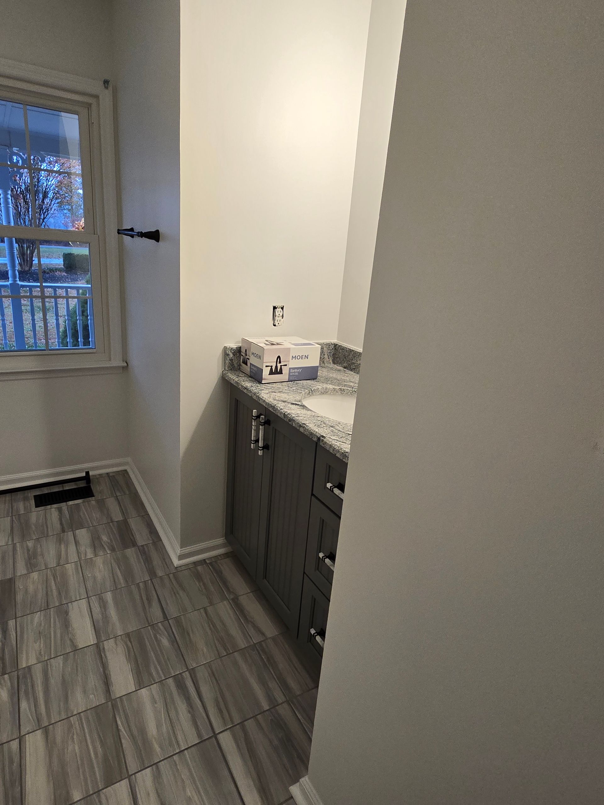 Bathroom with gray vanity, countertop, window, and gray tiled floor.