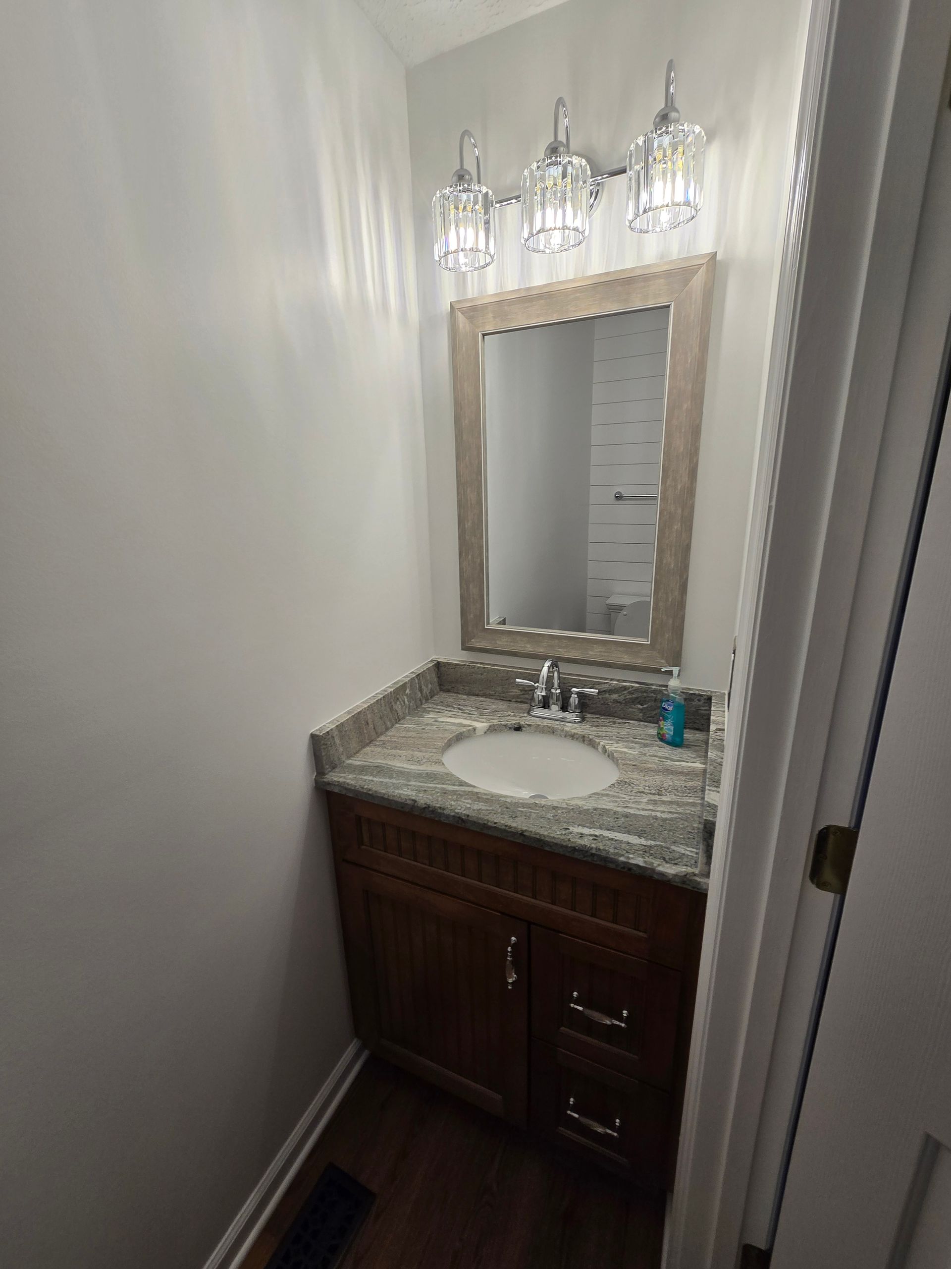 Small bathroom with a vanity, mirror, and overhead lighting.