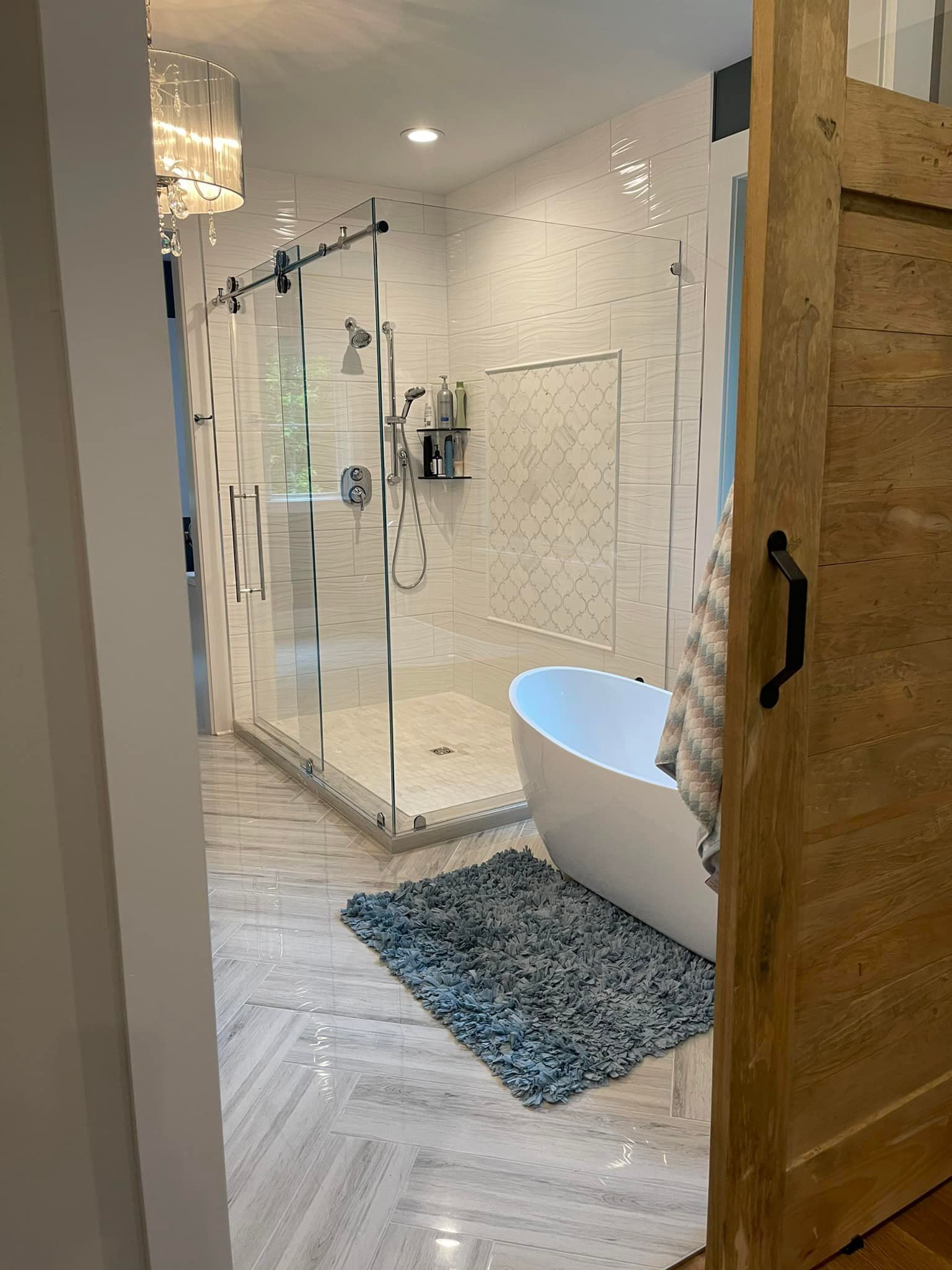 Bathroom with a large walk-in shower, freestanding tub, and a wooden sliding door.