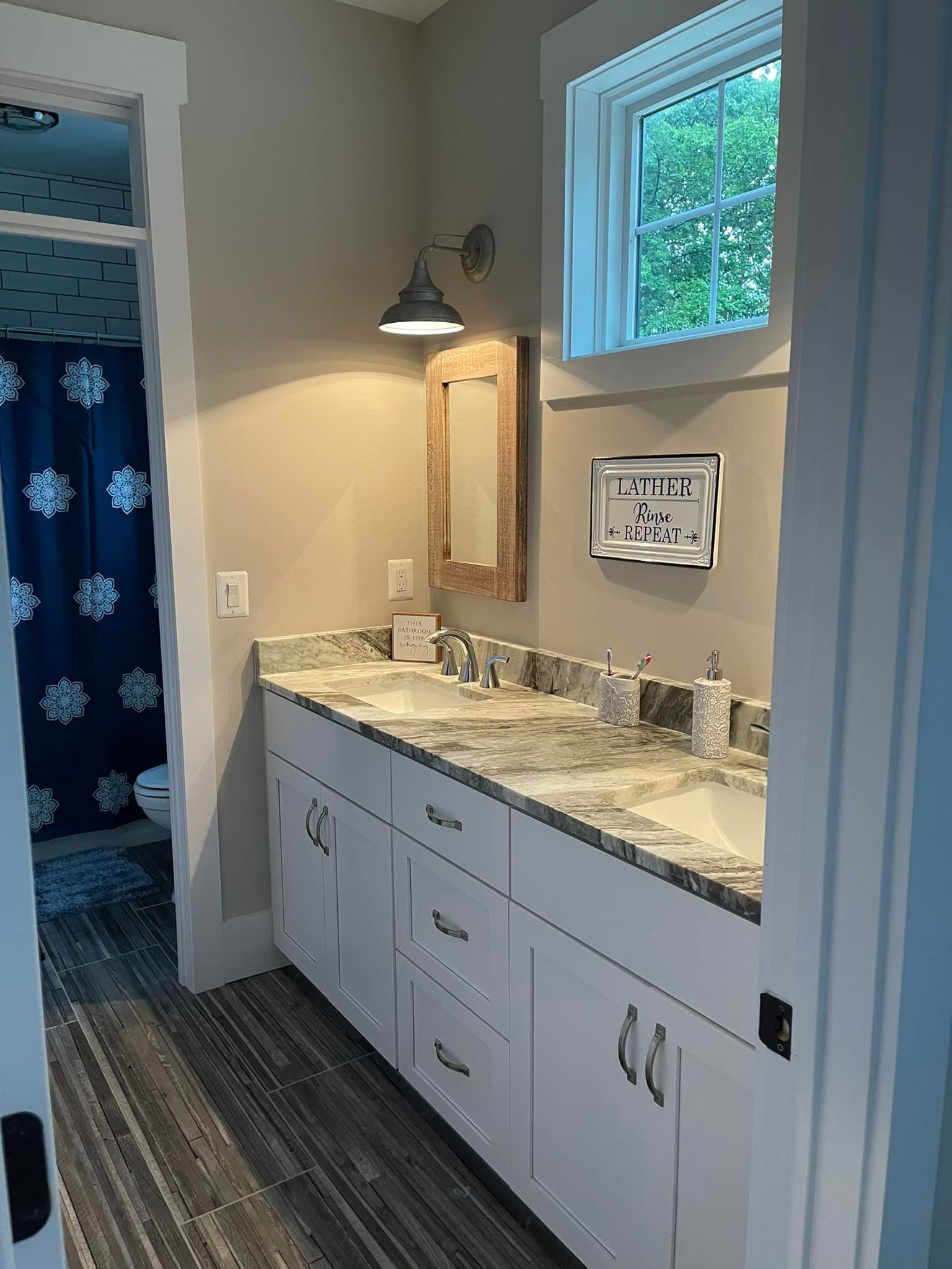 Bathroom with a white double vanity, granite countertop, and small window.
