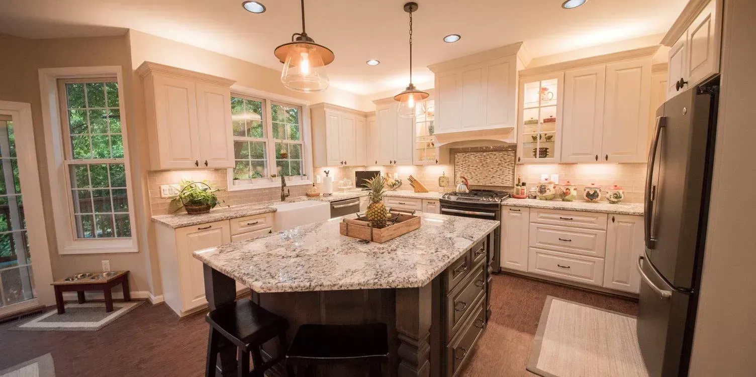 A kitchen with an island, cabinets, and appliances. It has a neutral color palette with warm lighting.