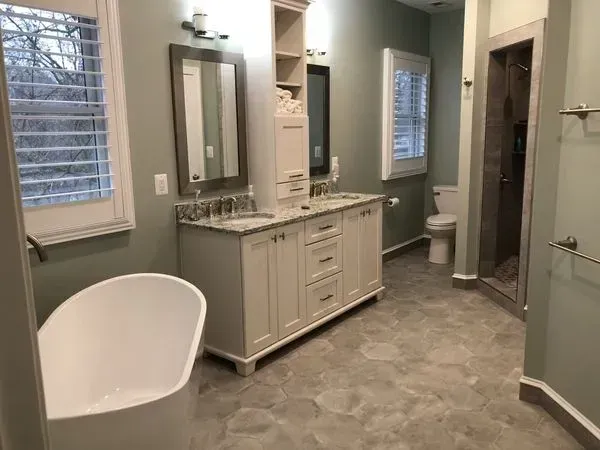 Bathroom with a freestanding tub, double vanity, and a glass-enclosed shower. Gray walls and tile.