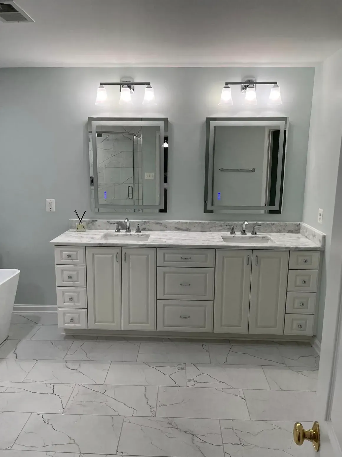 Bathroom with white double vanity, marble countertop, two mirrors, and overhead lighting.