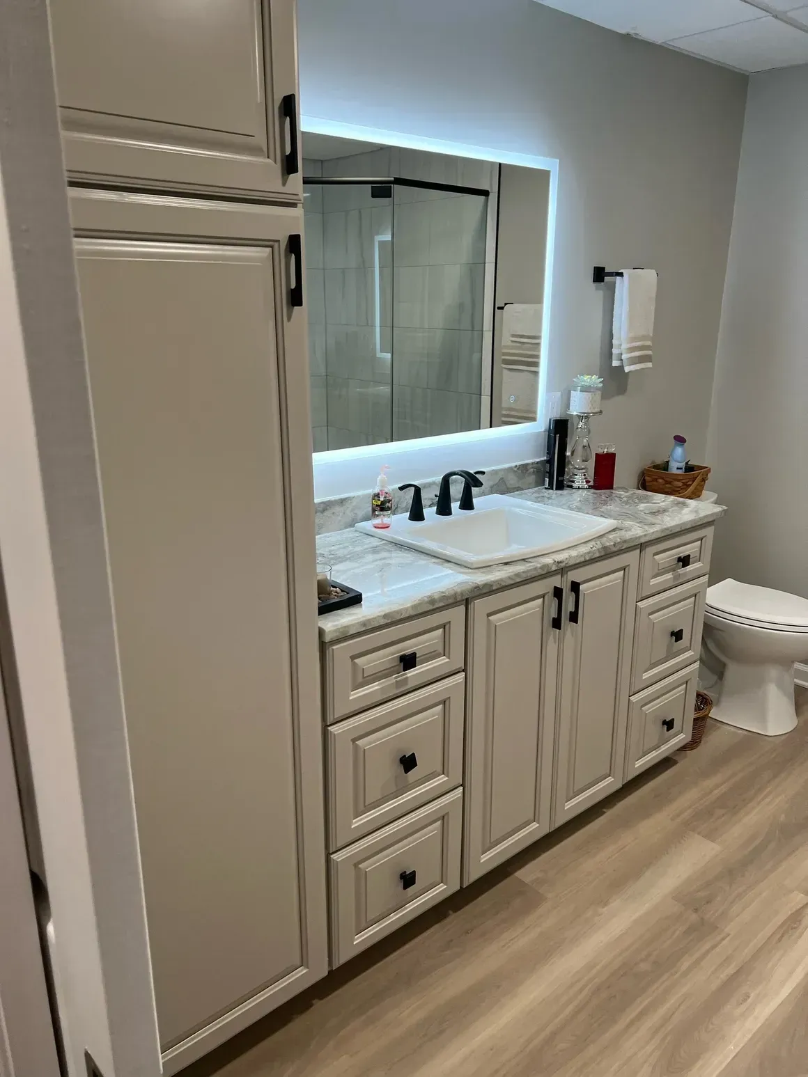 Bathroom with white cabinets, large mirror with LED lighting, and a toilet.