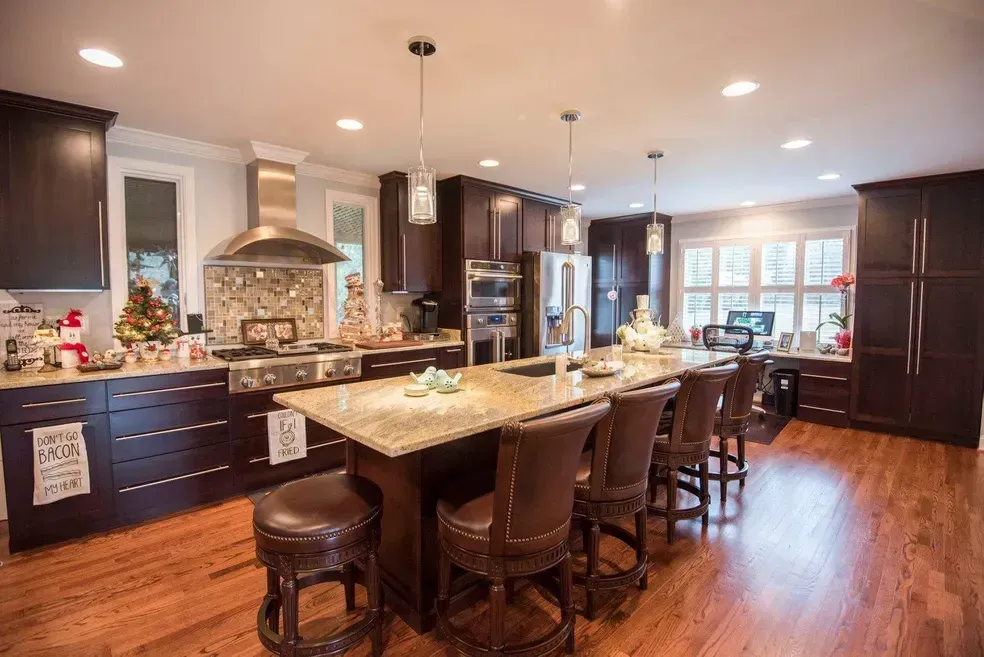 Spacious kitchen with dark wood cabinets, stainless steel appliances, large island with seating, and hardwood floors.