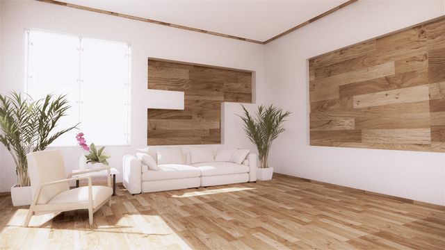 Bright modern living room with wood panel accents, white furniture, plants, and hardwood floors.