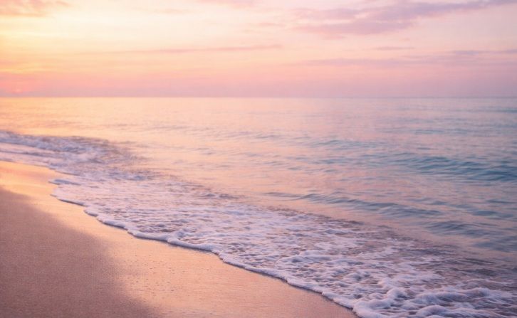 Gentle ocean waves rolling onto smooth sand at sunrise in Post Falls