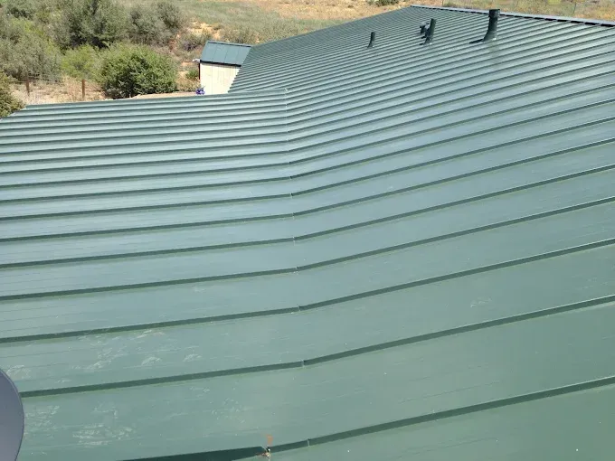 Green metal roof on a building, angled lines, outdoor setting.