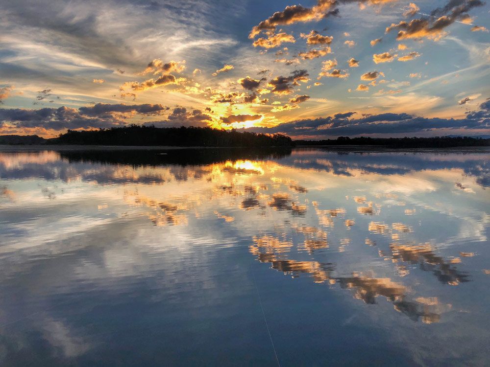 A Sunset Over a Lake With Clouds Reflected in the Water — Nabiac Water Carriers in Old Bar, NSW