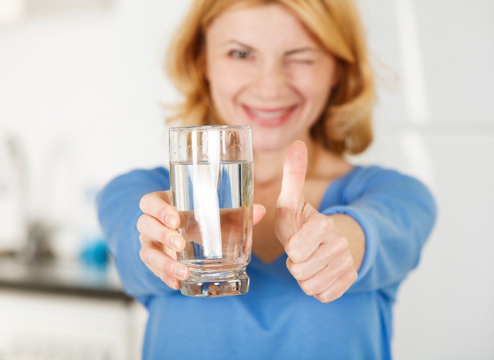 Woman Showing Thumbs Up Sign And Holding A Glass Of Water — Nabiac Water Carriers In Belbora NSW