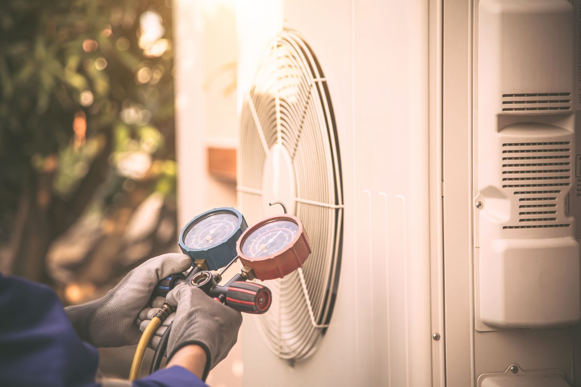 A man is using a gauge to check the pressure of an air conditioner.