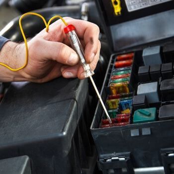 A person is working on a fuse box with a screwdriver - Curry Truck & Auto