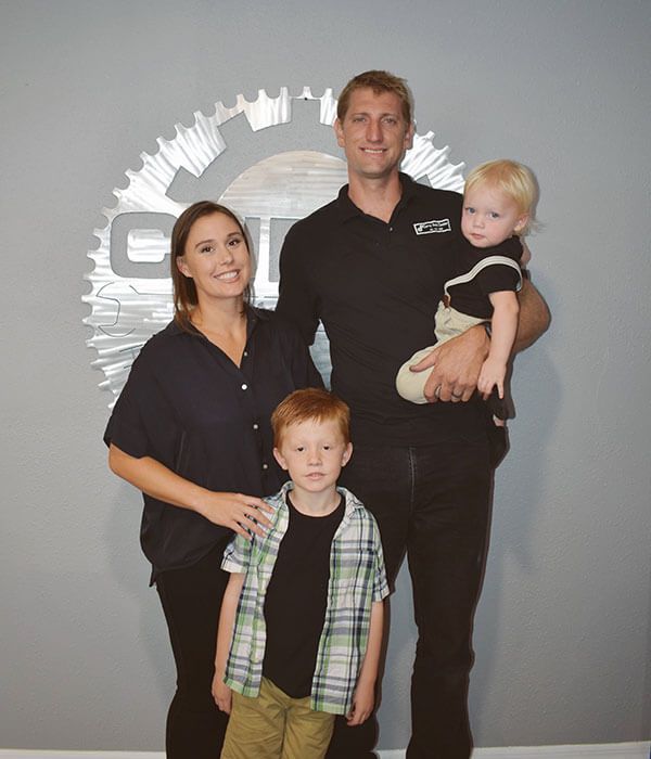 A family poses for a picture in front of a logo - Curry Truck & Auto