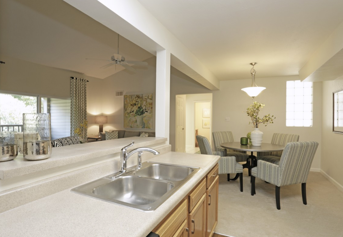 Kitchen with a sink and countertop looking towards a dining area with a table and chairs.