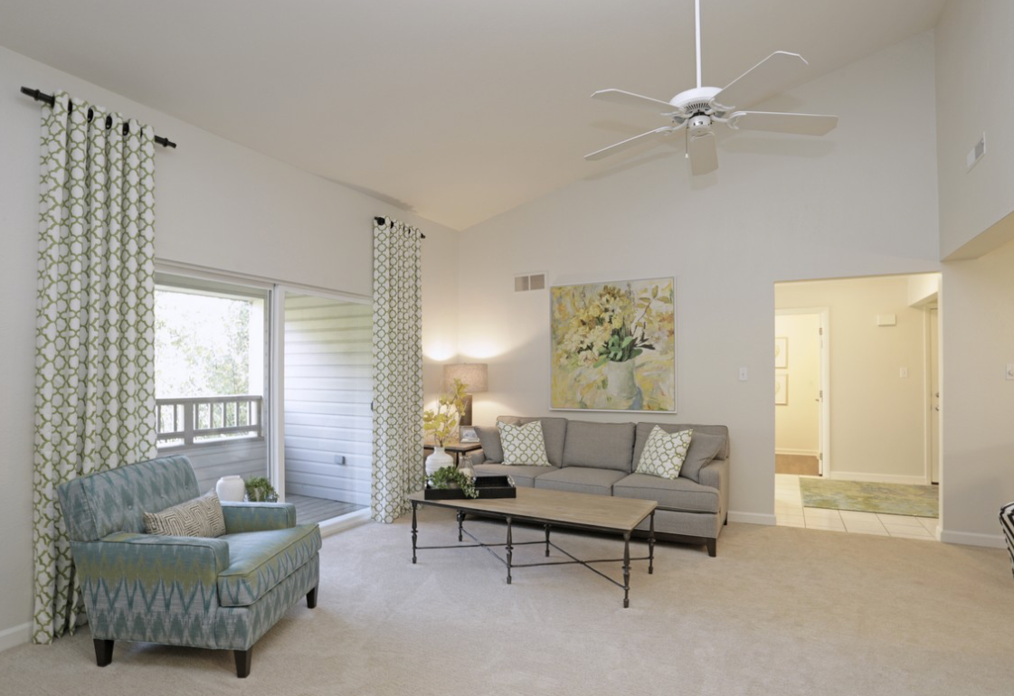 Living room with a balcony, gray sofa, blue armchair, neutral colors.