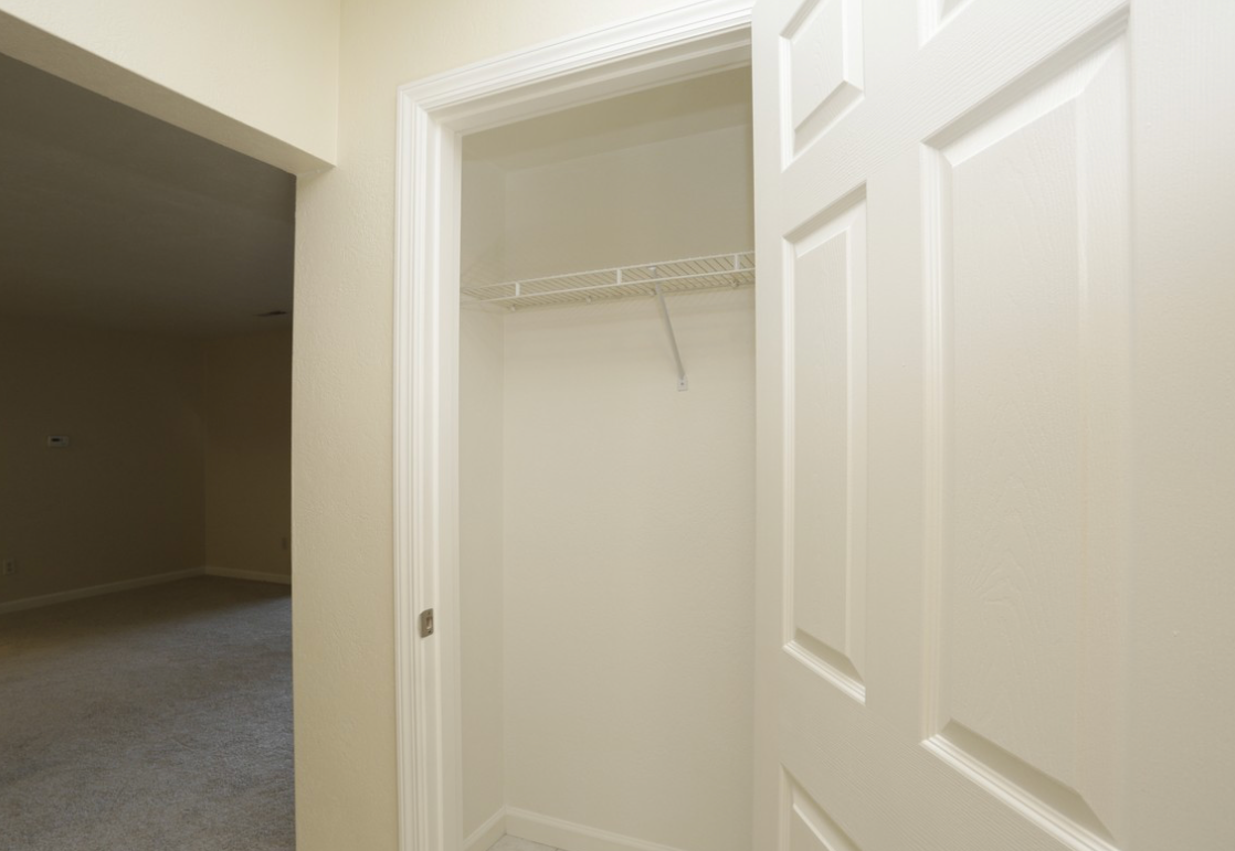 White closet doorway with wire shelf, opening into a room.