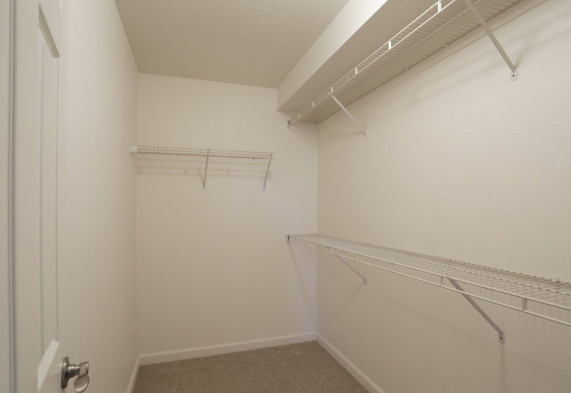 Empty white closet with wire shelving and carpet flooring.