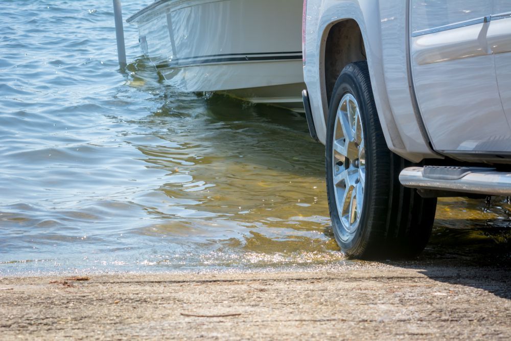 A White Truck Is Parked Next To A Boat In The Water — Torquay & Anglesea Accident Towing Centre In Torquay, VIC