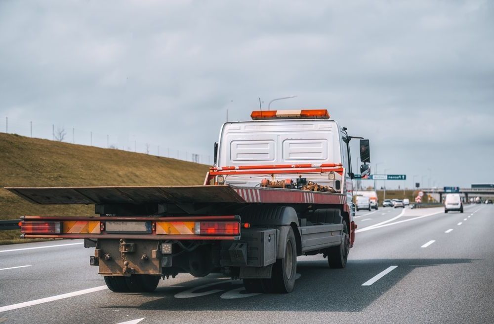 A Tow Truck With A Flat Bed Is Driving Down A Highway — Torquay & Anglesea Accident Towing Centre In Torquay, VIC